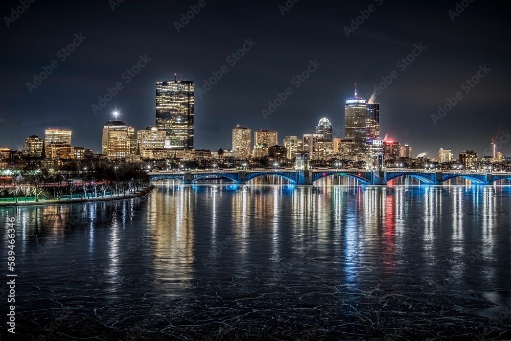 a night shot of the city from across the river with ice on the water