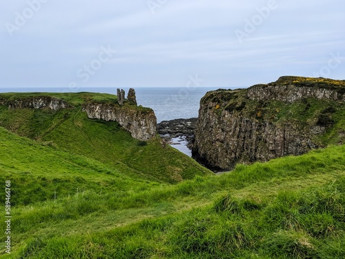 Dunseverick castle with green grass on rocky cliffs gloomy seascape background