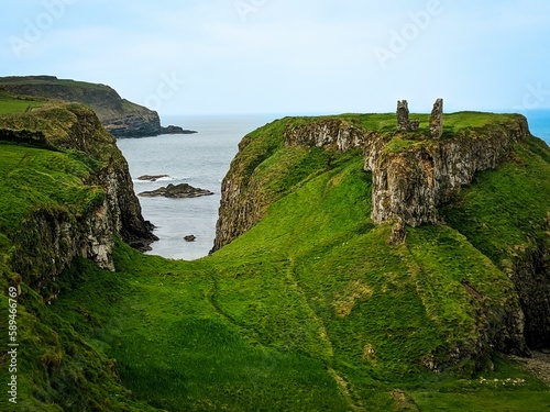 Dunseverick castle with green grass on rocky cliffs gloomy seascape background photo