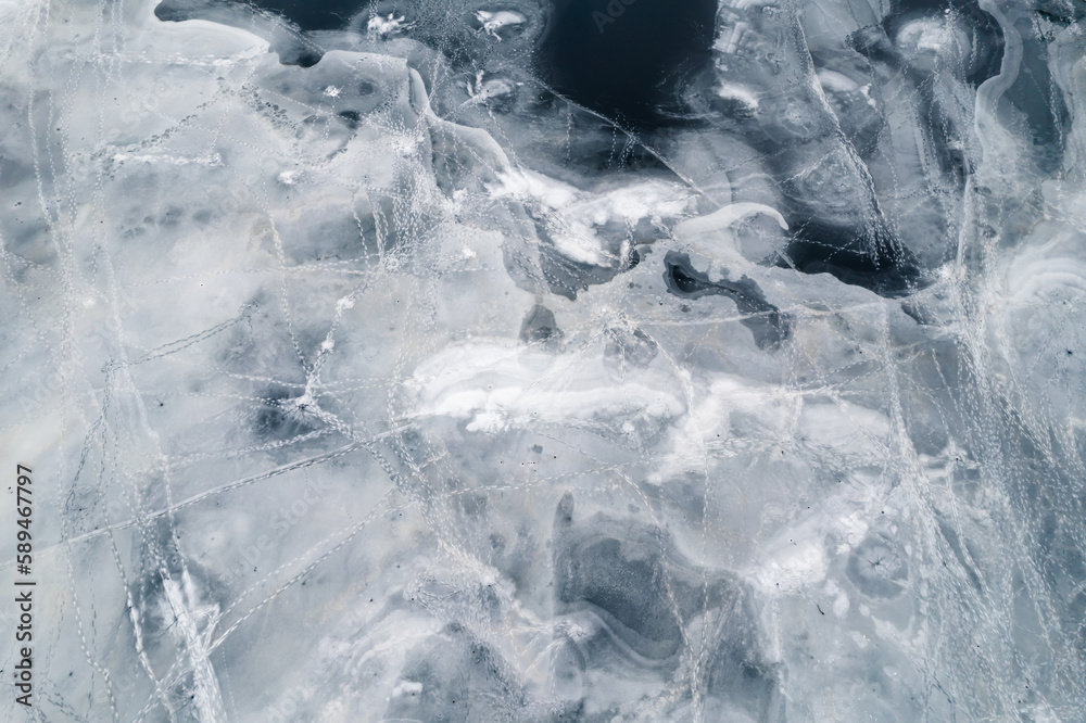 Obraz premium Top view of the frozen ice surface of the winter lake. Frozen pattern texture stripes and holes 