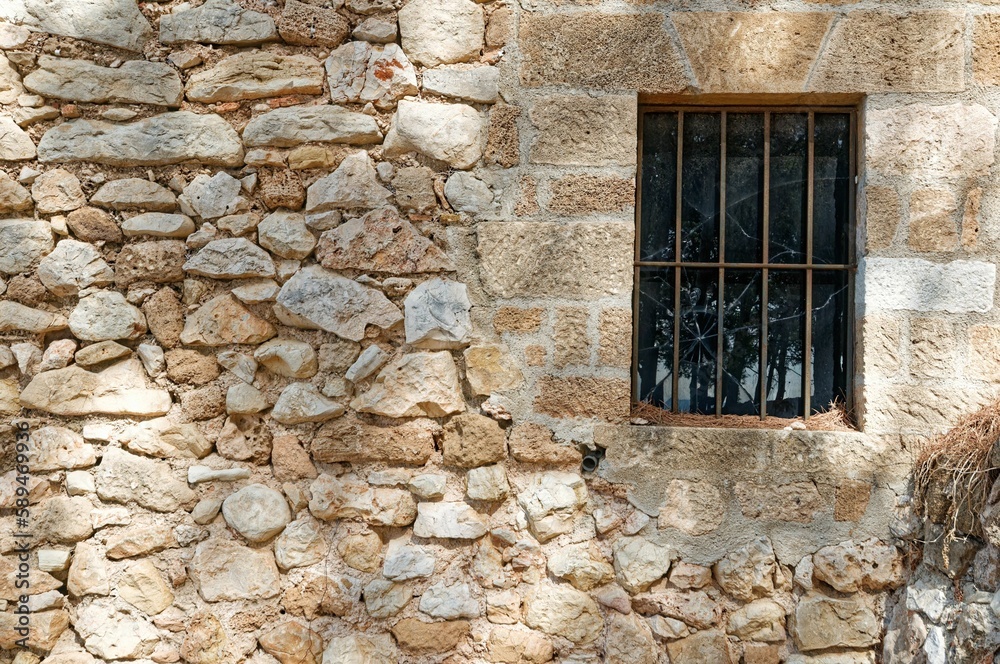 Stone wall with an old broken window and a lattice
