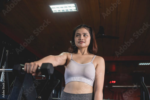 A serious young woman does a set of alternate front dumbbells raises. Training and toning shoulder muscles at the gym.