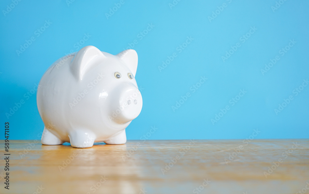 Fototapeta premium White Piggy bank on blue background with copy space. Saving money concept. 
