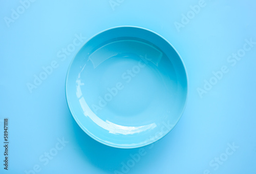 Flat lay view of empty blue ceramic plate on blue background. 