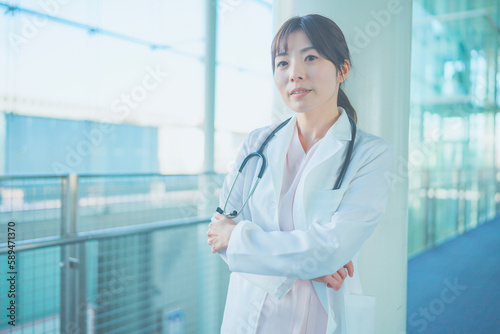 柱にもたれかかって考える白衣を着た女性医療従事者 photo