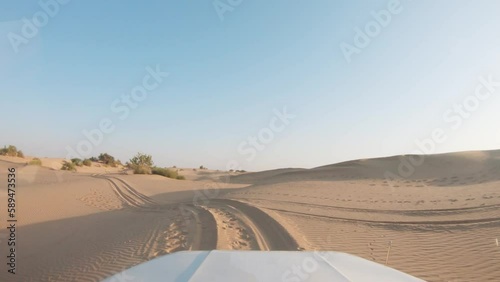 4K POV of a vehicle dune bashing on the sand dunes of the Thar desert at Jaisalmer in Rajasthan, India. Car moves on the desert during the day. Extreme adventure in the desert background. photo