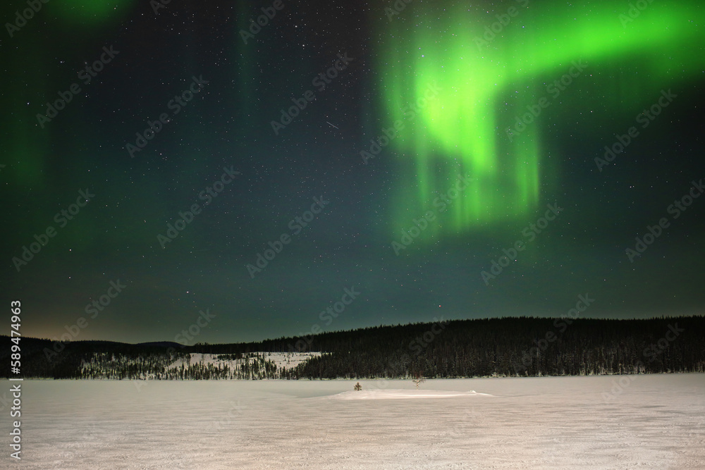 Green aurora curtains above frozen lake in northern Sweden