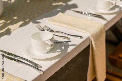 Closeup shot of clean cutlery, tea cups, saucers, and cups set up on a table