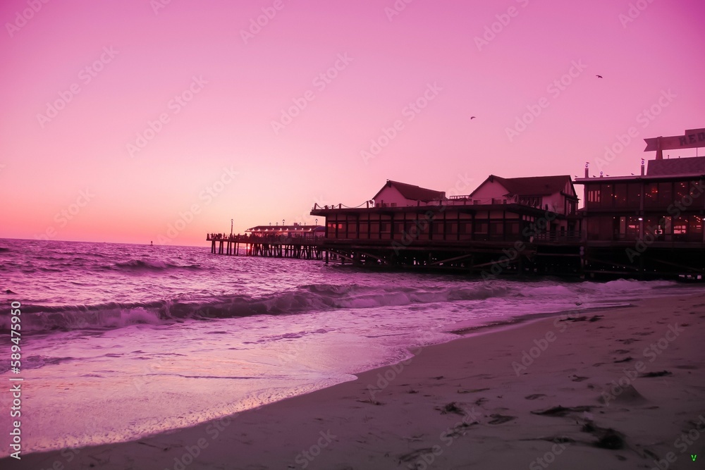Empty beach with buildings at sunset in purple shades.