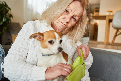 Sad senior woman with a dog showing her empty wallet