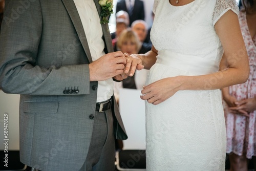 Groom at the wedding puts on a ring to the pregnant bride