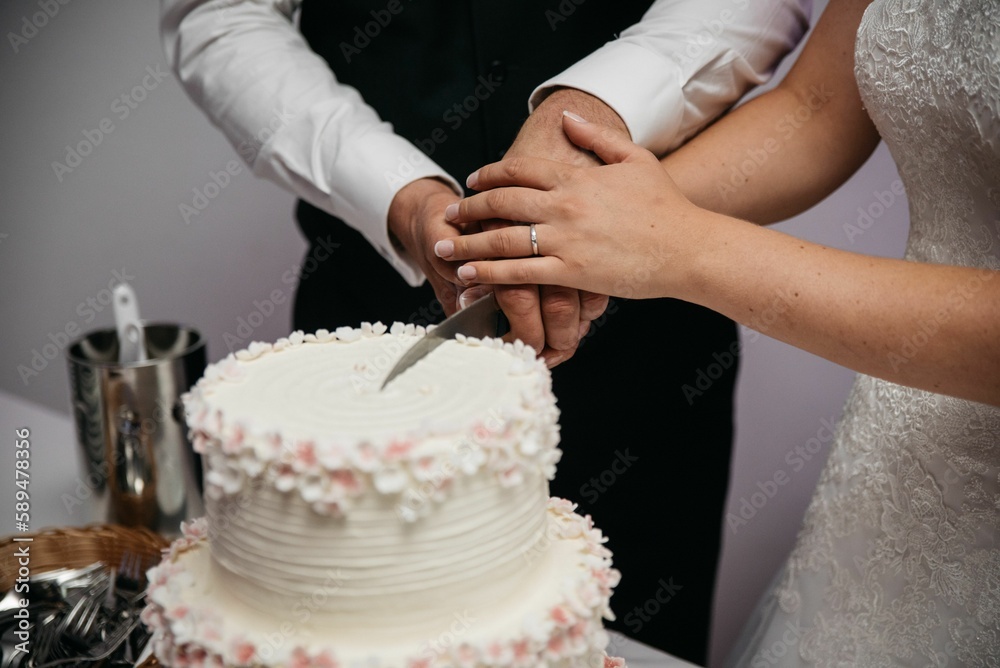 Closeup of bride's and bridegroom's hands cutting wedding cake Closeup of bride's and bridegroom's hands cutting wedding cake