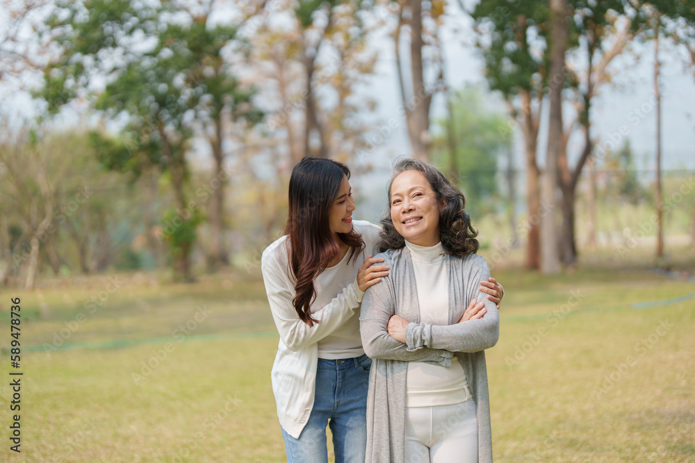 Grown daughter with aging mother showing love and walking together in the parkland