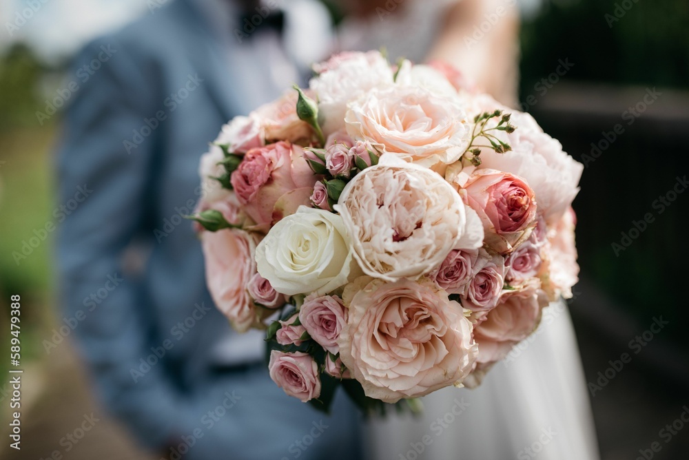 Selective focus of the bride holding a beautiful pink flowers' bouquet standing near the groom