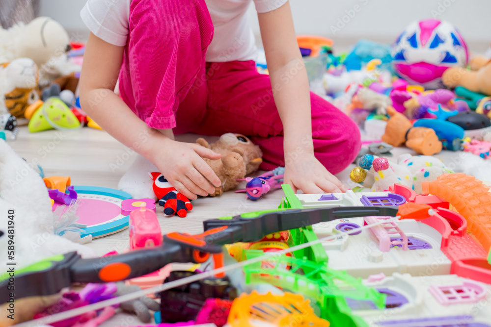 many toys are scattered on the floor in a big pile. The girl plays with toys. Different children, hands, large and small animals, a house. many toys are scattered on the floor in a big pile. The girl plays with toys. Different children, hands, large and small animals, a house.