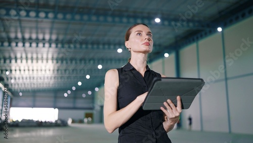 Caucasian woman manager using tablet for work and recheck the orderliness or stock of product in the factory or warehouse