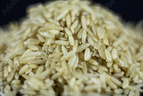 Studio macro shot of a pile of brown rice, also called complete, integral or wholegrain rice, with a blurred background. Brown rice is richer in fiber and used in several diets.