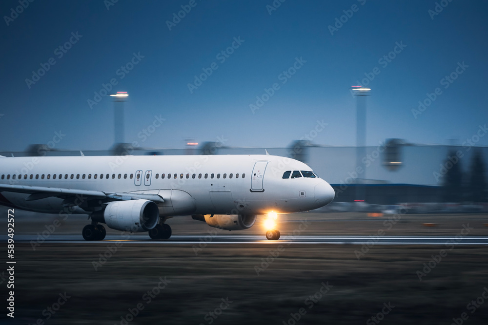 Commercial airplane during take off on airport runway at night. Plane in blurred motion. .