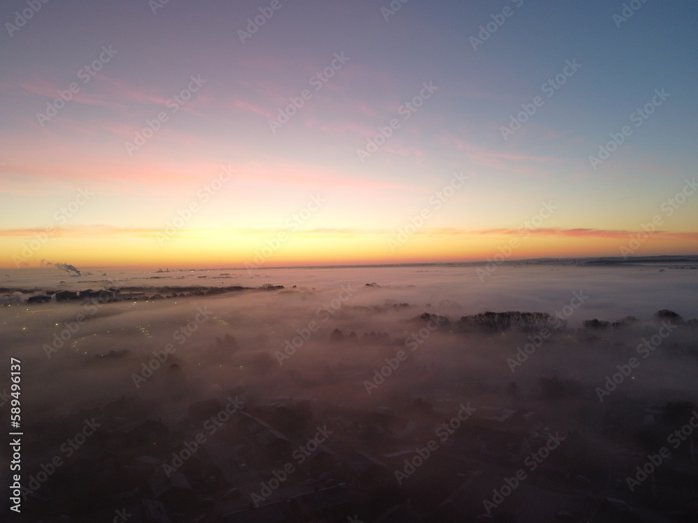 Cloud inversion covering an industrial setting during sunrise