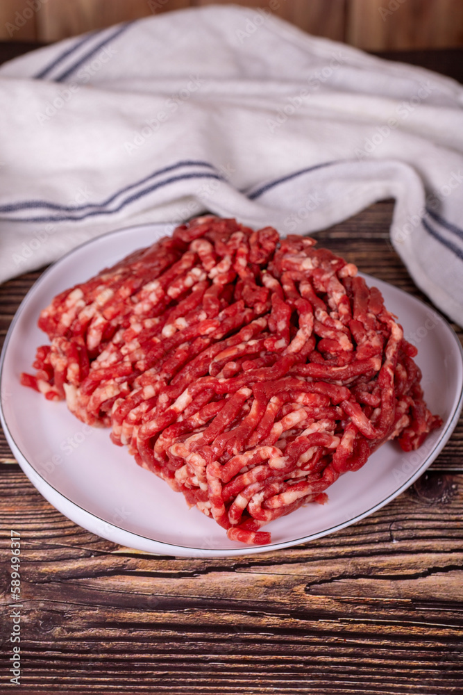 Beef minced on the plate. Fresh ground beef on wood background. Close up Beef minced on the plate. Fresh ground beef on wood background. Close up
