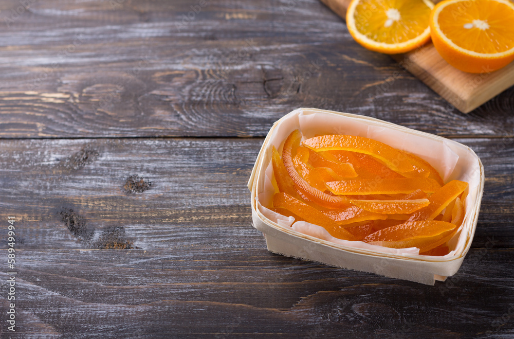 Wicker birch basket with candied oranges and fresh juicy oranges on wooden background Wicker birch basket with candied oranges and fresh juicy oranges on wooden background