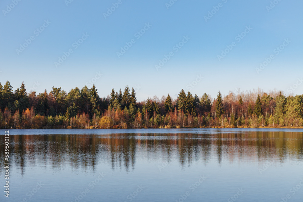 Fall colours of forest reflected in the waters of a lake Fall colours of forest reflected in the waters of a lake