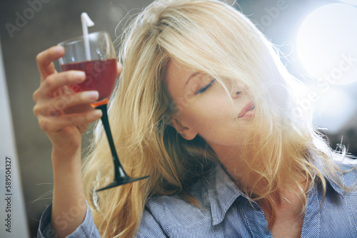 Carefree blond woman tasting and drinking wine at the party photo