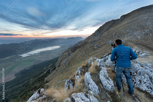 View of a person standing on the rocks taking photos from mountain top at Matese lake, Campania, Italy. photo