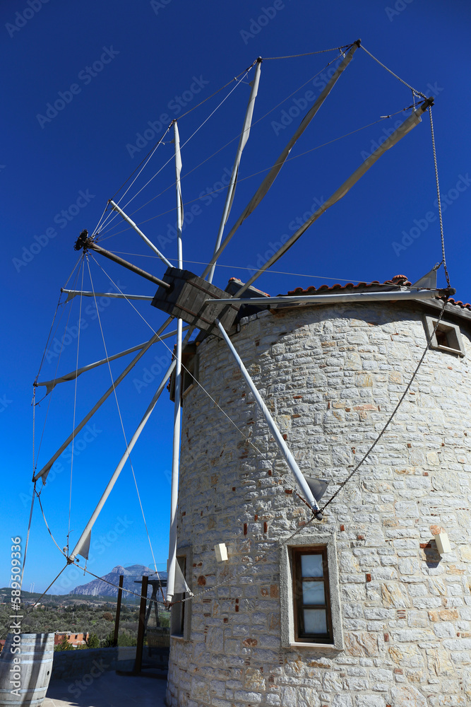 Low angle shot of a restored old school stone windmill with sails. Clear blue sky background, copy space for text, close up.