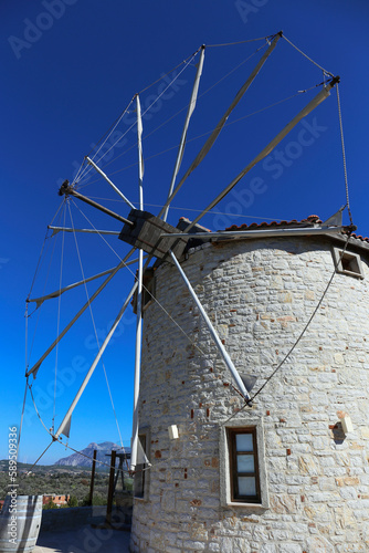 Low angle shot of a restored old school stone windmill with sails. Clear blue sky background, copy space for text, close up.