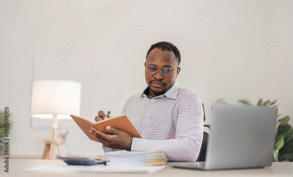 Portrait of handsome African black young business man working on laptop at office desk. Portrait of handsome African black young business man working on laptop at office desk.