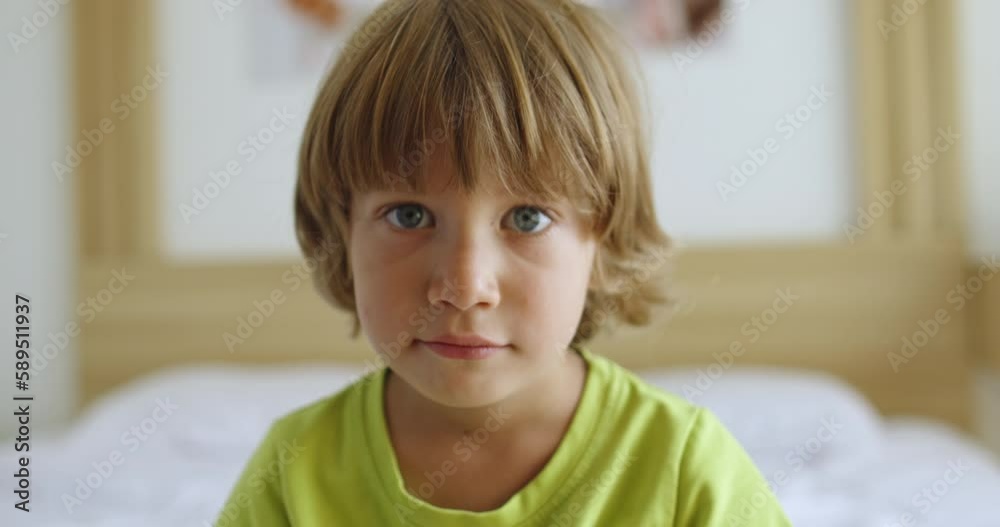 Portrait of boy sits on the bed, attentively looks, listens and smile Portrait of boy sits on the bed, attentively looks, listens and smile