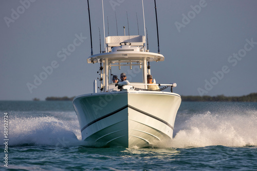 Center console fishing boat approaching head-on at speed.