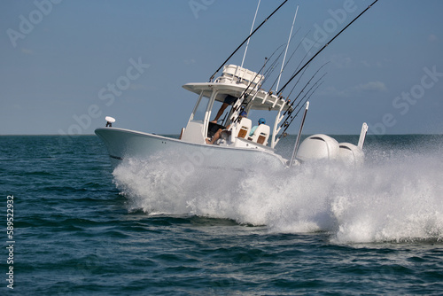 Center console fishing boat turning hard and throwing spray.