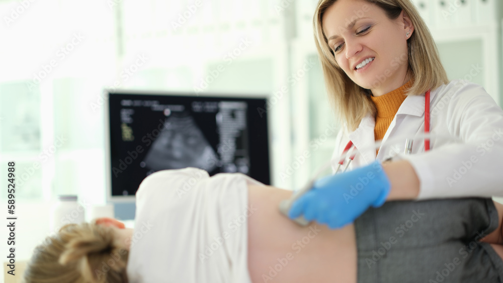 Fototapeta premium Doctor pediatrician conducting ultrasound examination of kidneys of child in clinic. Instrumental diagnosis of diseases and genitourinary system in children concept 