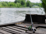 Fishing on the banks of a river or lake, outdoor recreation. Spinning rod reel lies on a wooden pier