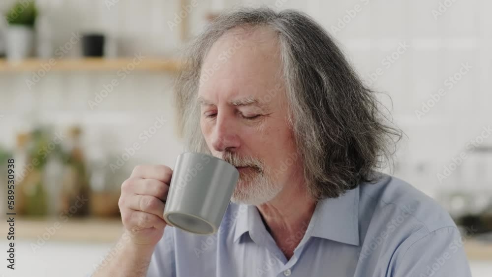 Elderly gray-haired man enjoys delicious fragrant coffee at home in the kitchen. Close-up Elderly gray-haired man enjoys delicious fragrant coffee at home in the kitchen. Close-up