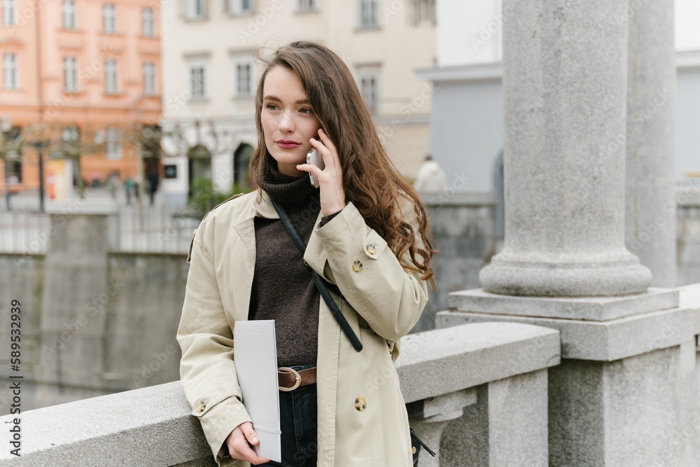 Fototapeta premium Young successful caucasian woman outside working remotely, having a business call