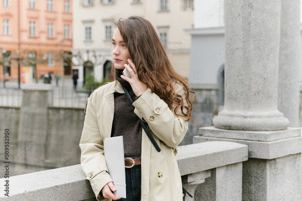 Fototapeta premium Young successful caucasian woman outside working remotely, having a business call