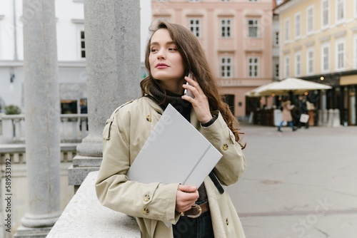 Young successful caucasian woman outside working remotely, having a business call