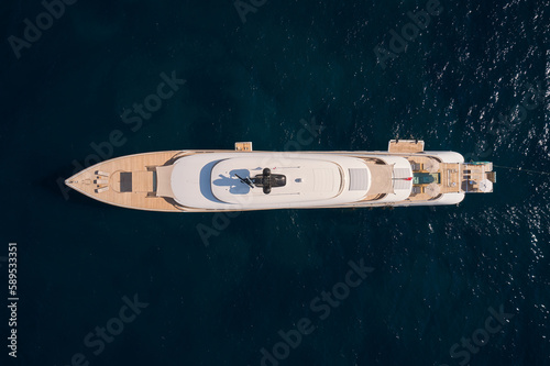 Innovative white big yacht anchored in the morning sun top view. Mega yacht on a dark background aerial view. © Berg