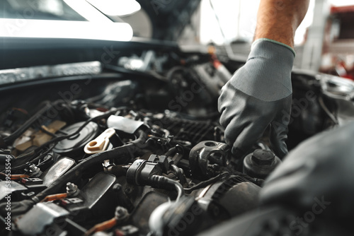 Schilderij op canvas Close up of mechanic's hands repairing car engine in car service
