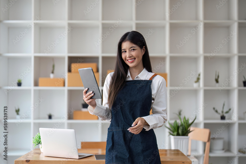 Startup SME small business entrepreneur of freelance Asian woman using tablet and box to receive and review orders online to prepare to pack sell to customers, online sme business ideas Startup SME small business entrepreneur of freelance Asian woman using tablet and box to receive and review orders online to prepare to pack sell to customers, online sme business ideas