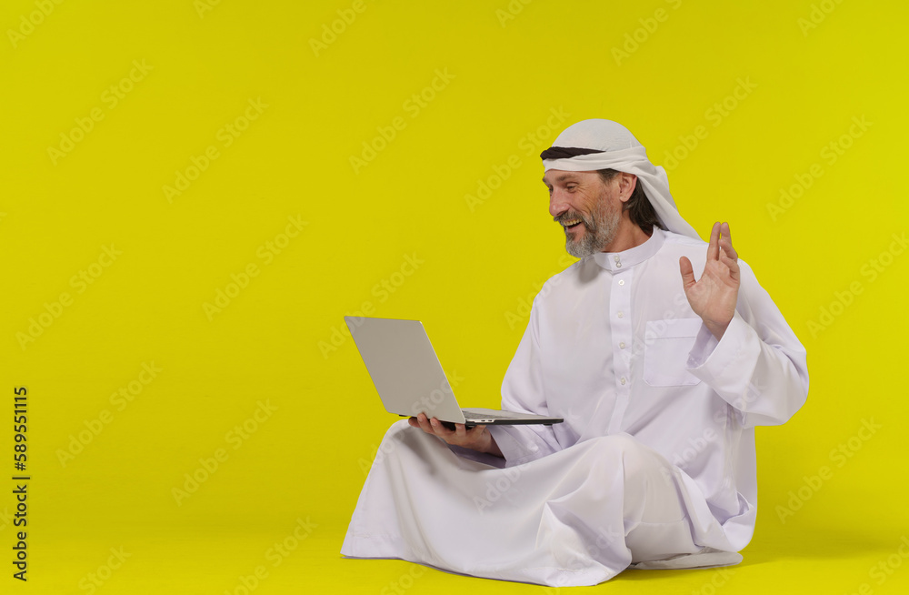 Concept online communication. Muslim person sitting on floor greets someone with their palm raised while holding a laptop in their hand. Copy space allows for easy customization and versatility and Concept online communication. Muslim person sitting on floor greets someone with their palm raised while holding a laptop in their hand. Copy space allows for easy customization and versatility and