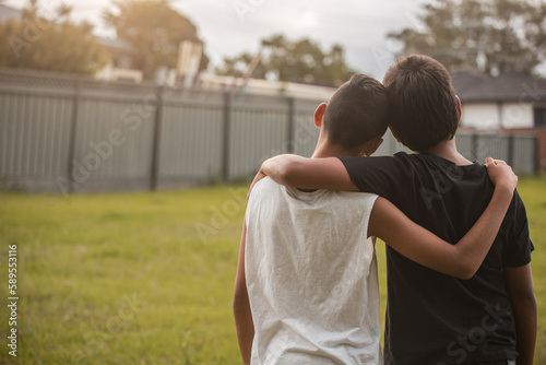 Two aboriginal boys with their arms around one another looking away photo