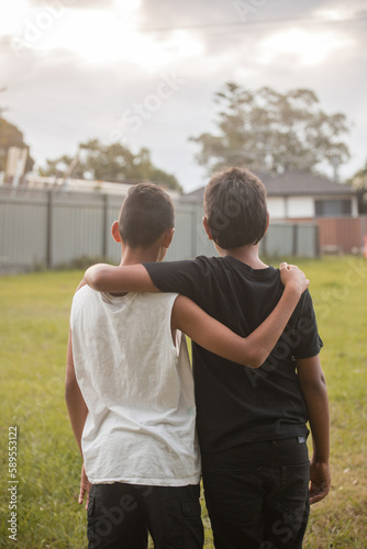 Two aboriginal boys with their arms around one another looking away photo