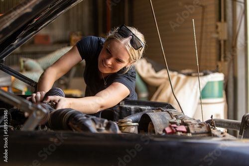 young australian tradesperson mechanic fixing car engine in automotive repair garage photo