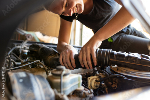 young female tradesperson mechanic fixing car engine in automotive repair garage photo