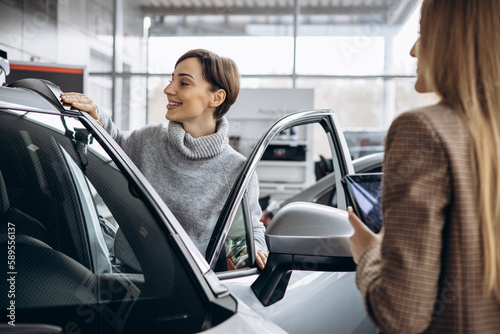 Woman in car showroom talking to salesperson