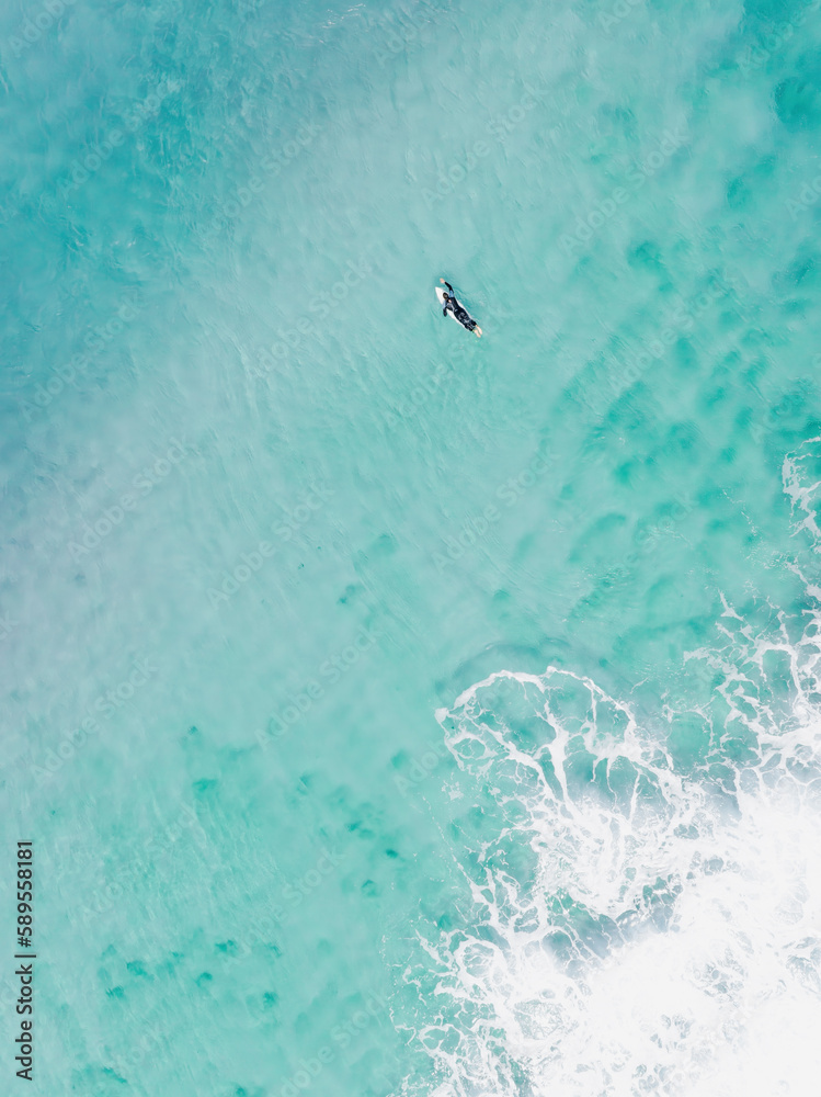 View from above, stunning aerial view of a person surfing on a turquoise ocean. Fuerteventura, Canary Islands, Spain.